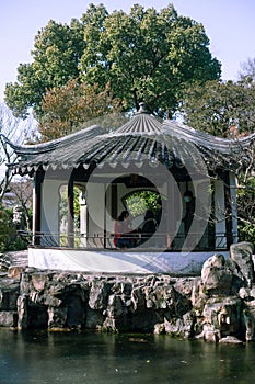Vertical shot of people in a pavilion in Classical Gardens of Suzhou.