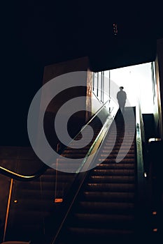 Vertical shot of the person from behind on the underground escalator climbing up