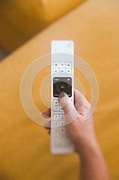 Vertical shot of a person holding a remote control with a blurred background