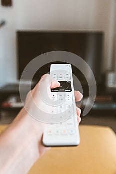 Vertical shot of a person holding a remote control with a blurred background