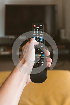 Vertical shot of a person holding a remote control with a blurred background