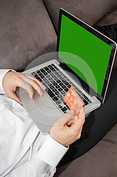 Vertical shot of a person inputting details of its credit card in the laptop