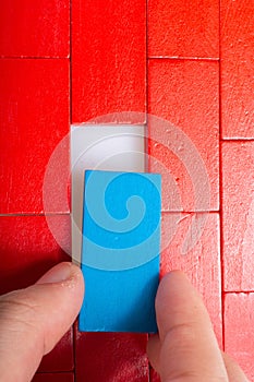 Vertical shot of a person putting a blue piece of a red puzzle under the lights