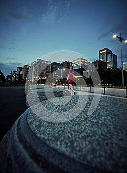 Vertical shot of a person running in the street at evening and architectures in the background