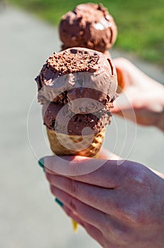 Vertical shot of a person& x27;s hands holding a chocolate ice cream cone on a sunny day