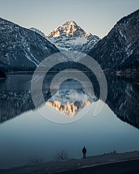 Vertical shot of a person standing by the Riffelsee Lake in the Matterhorn mountains in Switzerland