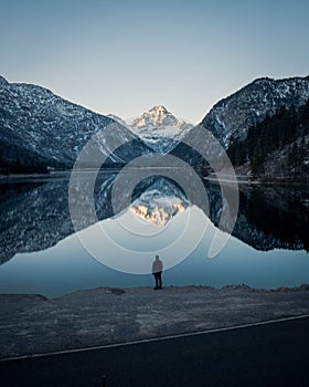 Vertical shot of a person standing by the Riffelsee Lake in the Matterhorn mountains in Switzerland