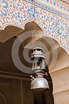 Vertical shot of a petromax kerosene lantern hang in the middle of an arch of a Buddhist building photo