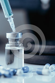 Vertical shot of pharmaceutical syringe with needle in a medicine and pills - illegal doping drugs