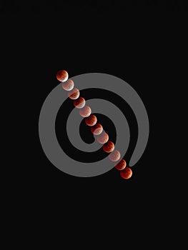 Vertical shot of the phases of a lunar eclipse in a dark black sky