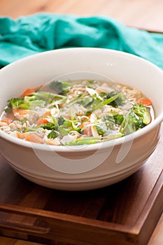 Vertical shot of pho soup with fresh chicken and vegetables, ramen noodles and onion