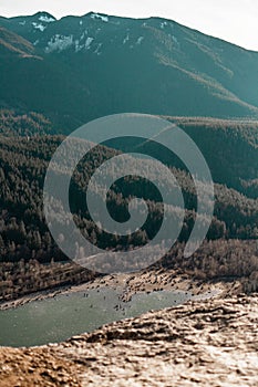 Vertical shot of a pond in the middle of forested mountains at daytime