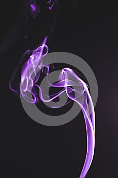 Vertical shot of purple smoke clouds on a dark background