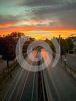 Vertical shot of the railway lines between the street under a beautiful sunset sky