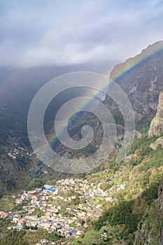 Vertical shot of the rainbow in the sky over the village captured in Madeira, Portugal