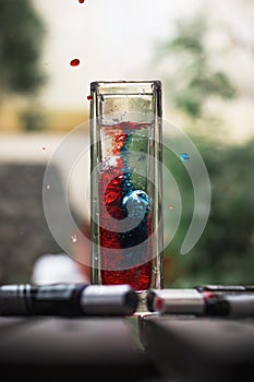 Vertical shot of red and blue ink mixing beautifully with water in a glass