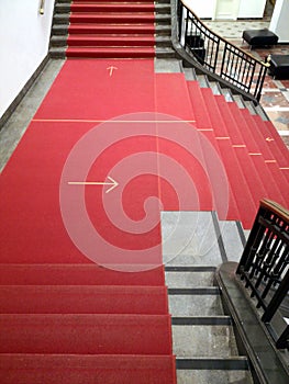 Vertical shot of a red stairway with the direction marked on the ground