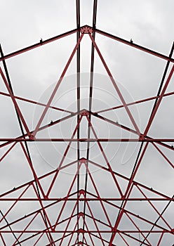 Vertical shot Red steel structure skeleton with cloudy sky in the background.