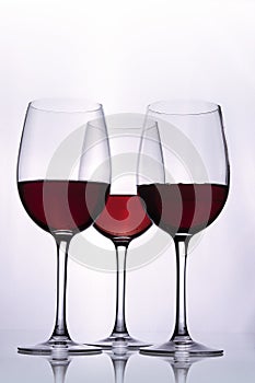 Vertical shot of red wine in three glasses on the table isolated on a white background