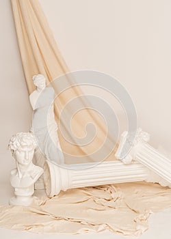 Vertical shot of the Renaissance epoch gypsum statues arranged with fabric on white background