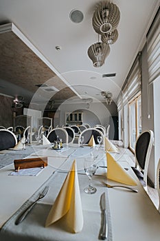 Vertical shot of restaurant tables and chairs with glassware and napkins