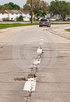 Vertical shot of a road with harmed asphalt coat and a car in the far, Manitoba, Canada photo