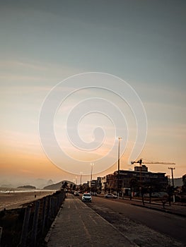 Vertical shot of a road surrounded by the sea and lights during the sunset in Rio de Janeiro