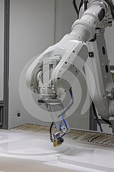 Vertical shot of a robot arm painting a wooden chair in a furniture factory. Robot arm painting spray. High-tech production