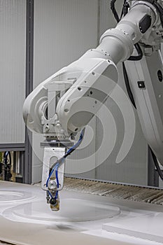 Vertical shot of a robot arm painting a wooden chair in a furniture factory. Robot arm painting spray. High-tech production