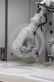 Vertical shot of a robot arm painting a wooden chair in a furniture factory. Robot arm painting spray. High-tech production