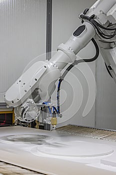 Vertical shot of a robot arm painting a wooden chair in a furniture factory. Robot arm painting spray. High-tech production