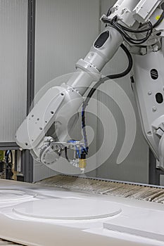 Vertical shot of a robot arm painting a wooden chair in a furniture factory. Robot arm painting spray. High-tech production