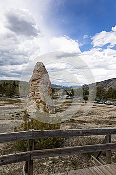 Vertical shot of rock formation in Mammoth Hot Springs with cars in the background