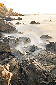 Vertical shot of rocks immersed into the ocean in vapour form in Menorca. Islas Baleares. Spain