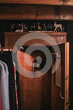 Vertical shot of a room with clothes a wooden door with deer statues and a black hanging phone