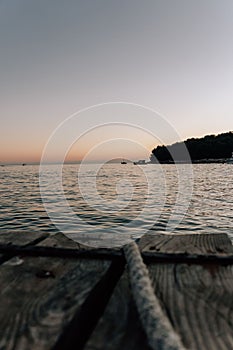 Vertical shot of a rope on a wooden pier on a sunset background