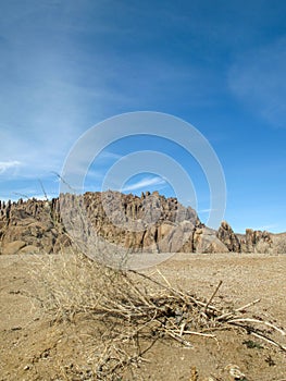 Vertical shot of rounded rocks of Alabama hills and the arid plains with dried twigs