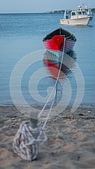 Vertical shot of a row boat sitting off a beach in a harbor