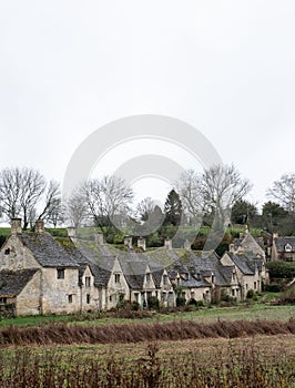 Vertical shot of a row of the historic quintessential Cotswold cottages in Bibury, England