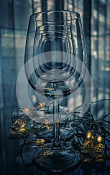 Vertical shot of a row of wine glasses on a smooth table surface with lights