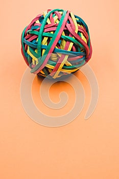 Vertical shot of a rubber ball made out of rubber bands isolated on an orange background