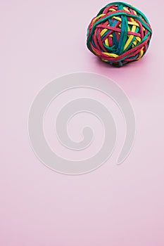 Vertical shot of a rubber ball made out of rubber bands isolated on a pink background