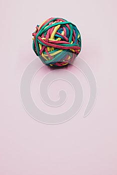 Vertical shot of a rubber ball made out of rubber bands isolated on a purple background