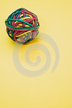 Vertical shot of a rubber ball made out of rubber bands isolated on a yellow background