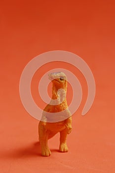 Vertical shot of a rubber dinosaur toy isolated on smooth red background