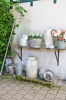 Vertical shot of rural floral decoration in pots and troughs on house wall for pleasant ambience