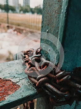 Vertical shot of rusty chains on an iron railing