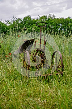 Vertical shot of rusty equipment in a grass field