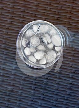 Vertical shot of s glass of ice water on a glass table on the balcony of the house