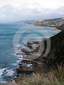 Vertical shot of a sea near the mountains under a cloudy sky in Australia